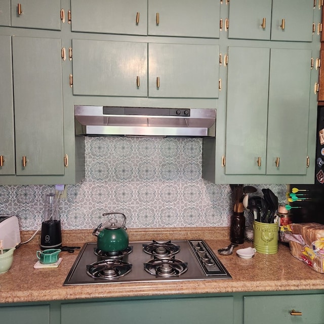 kitchen with ventilation hood, gas cooktop, green cabinets, and tasteful backsplash