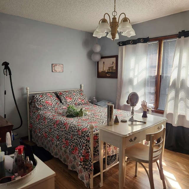 bedroom featuring a chandelier, wood finished floors, and a textured ceiling