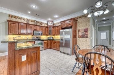 kitchen featuring dark stone countertops, stainless steel appliances, crown molding, and sink