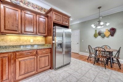 kitchen featuring tasteful backsplash, ornamental molding, a chandelier, stainless steel fridge with ice dispenser, and light tile patterned flooring