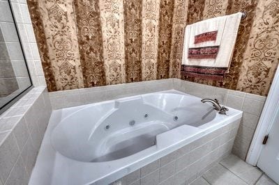 bathroom with tile patterned flooring and a relaxing tiled tub