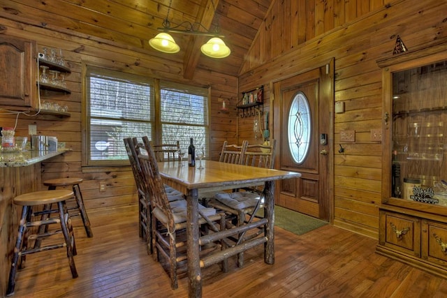 dining space with wooden ceiling, dark hardwood / wood-style floors, wooden walls, and vaulted ceiling