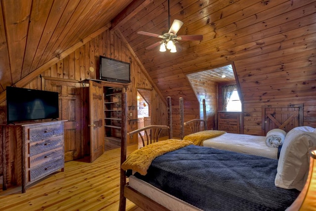 bedroom featuring wooden walls, light hardwood / wood-style floors, vaulted ceiling with skylight, and ceiling fan