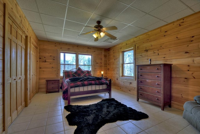 bedroom featuring multiple windows, a drop ceiling, light tile floors, and ceiling fan