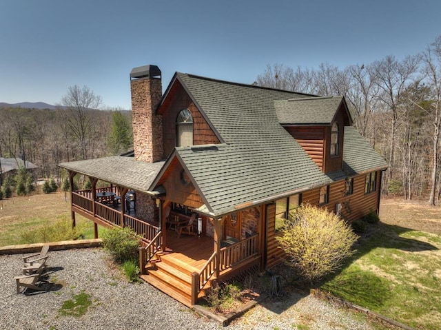 log-style house featuring a wooden deck and a front lawn