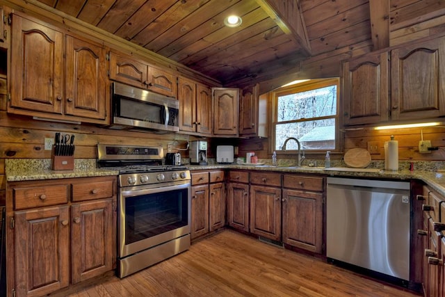 kitchen with appliances with stainless steel finishes, light hardwood / wood-style flooring, and wood walls