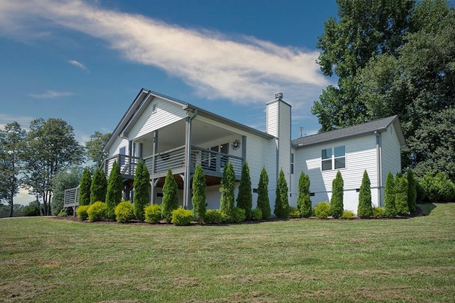 rear view of house with a balcony and a lawn