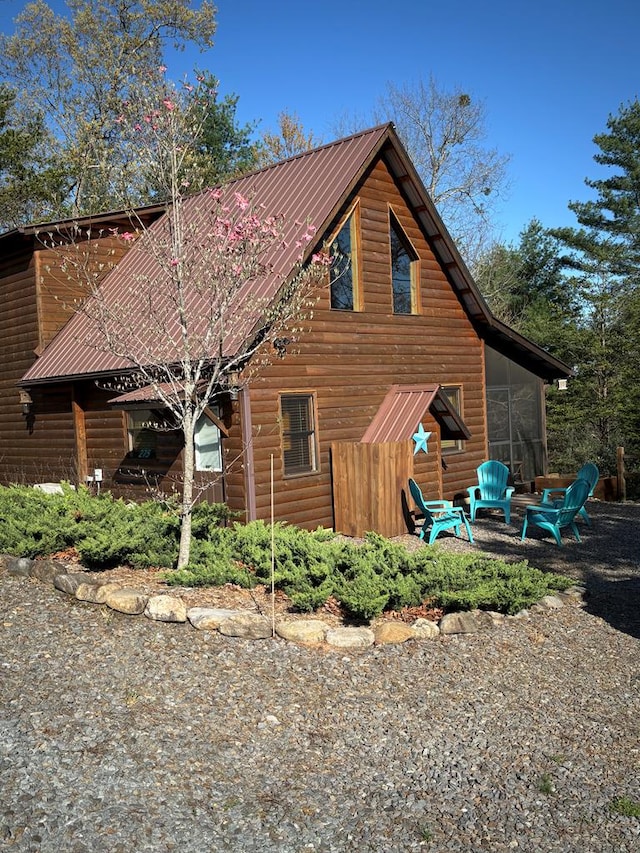 view of property exterior with metal roof, a sunroom, and faux log siding