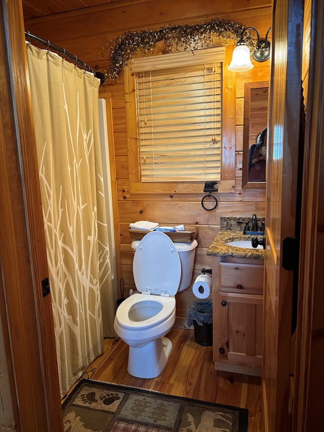 bathroom with vanity, a shower with curtain, toilet, wood finished floors, and wood walls