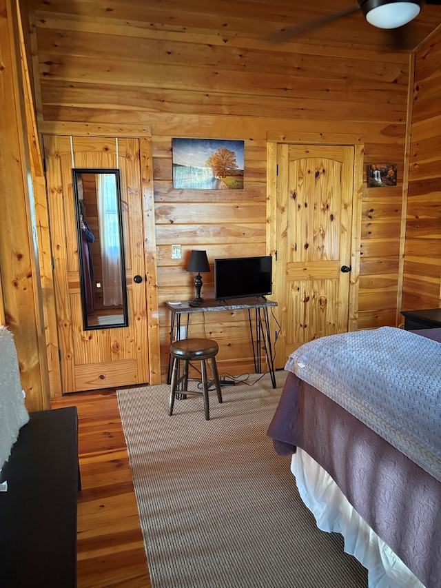 bedroom with wood finished floors and wood walls