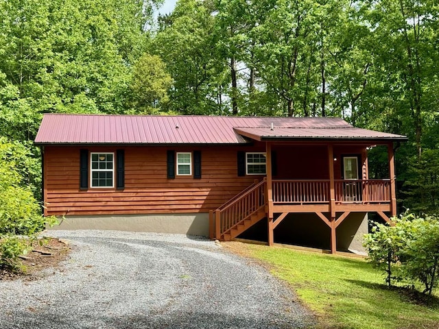 view of front facade with a porch, metal roof, and gravel driveway