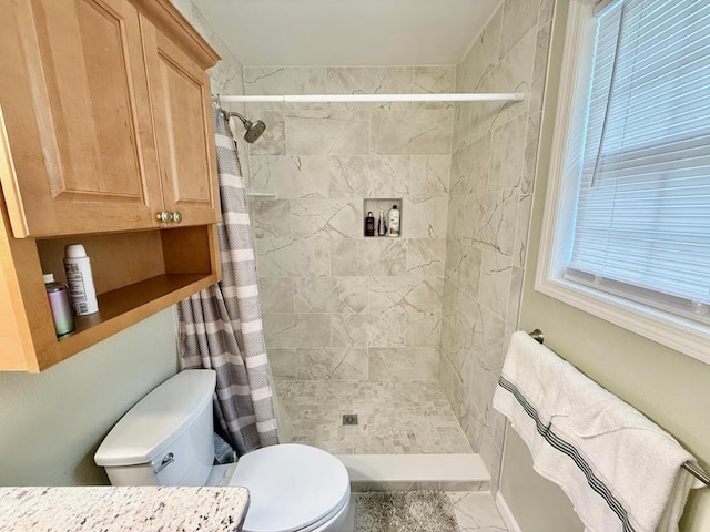 bathroom featuring tiled shower, toilet, and vanity