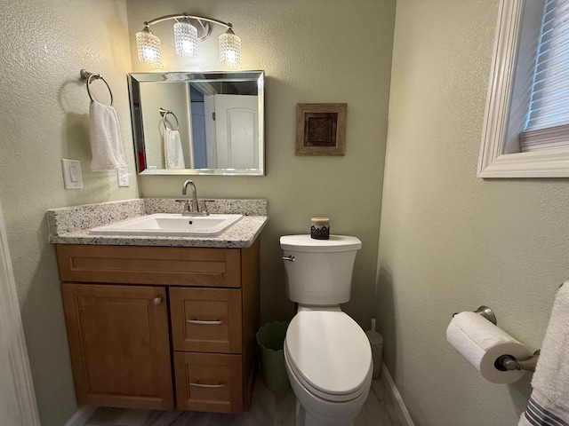 bathroom with vanity, toilet, and baseboards