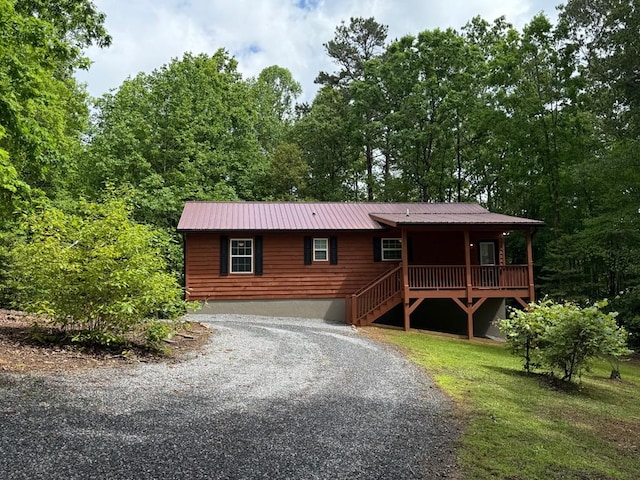 chalet / cabin featuring a porch, metal roof, and driveway