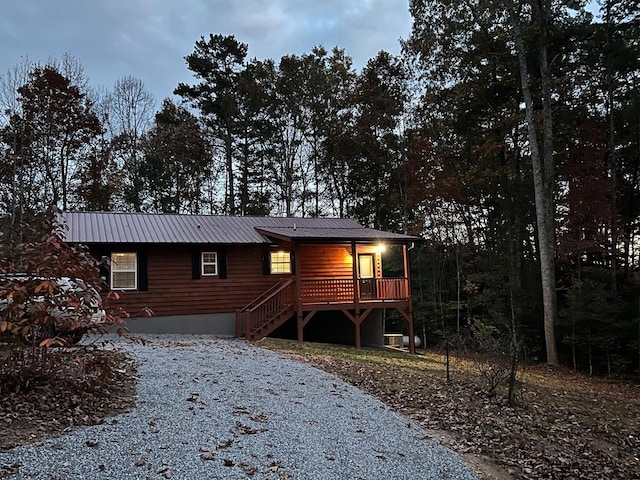 rustic home with metal roof, driveway, and a wooden deck