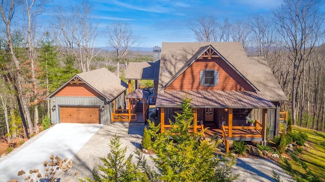 chalet / cabin featuring covered porch, an attached garage, and concrete driveway