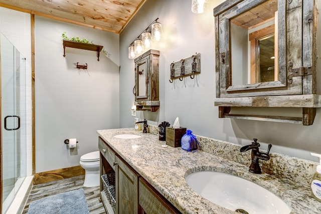 bathroom with wood finished floors, a stall shower, toilet, and a sink