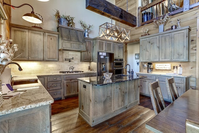 kitchen featuring light stone counters, dark wood-style floors, appliances with stainless steel finishes, and a sink