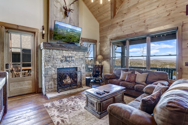 living area with high vaulted ceiling, a fireplace, wood walls, wood-type flooring, and wooden ceiling