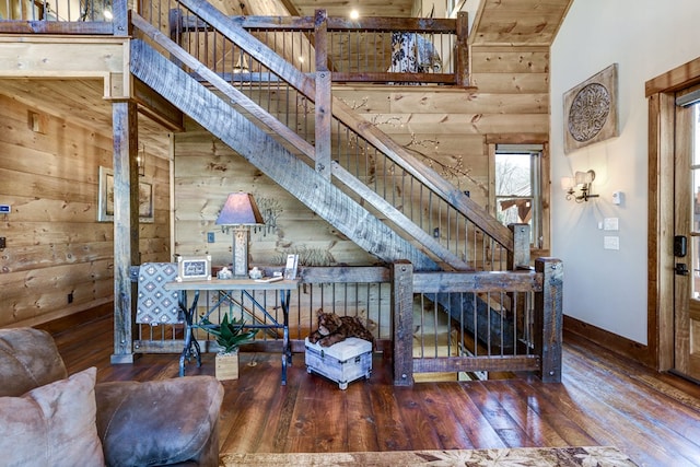 interior space featuring hardwood / wood-style flooring, stairway, baseboards, and wood walls