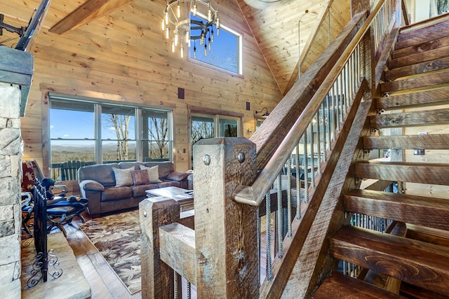 stairway with wooden walls, wood ceiling, and high vaulted ceiling