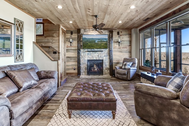 living area with a stone fireplace, wood ceiling, wood finished floors, and a healthy amount of sunlight