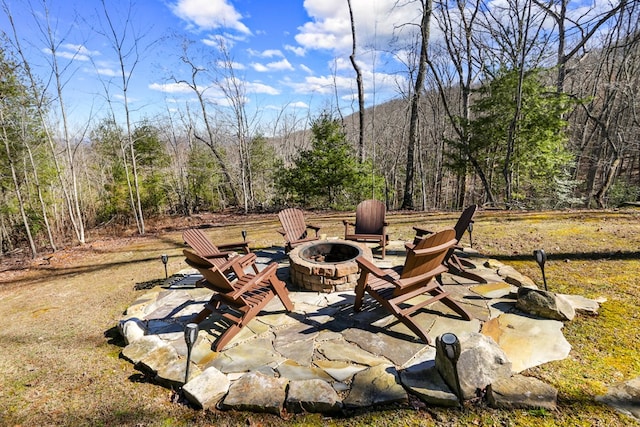 view of patio / terrace with a view of trees and an outdoor fire pit