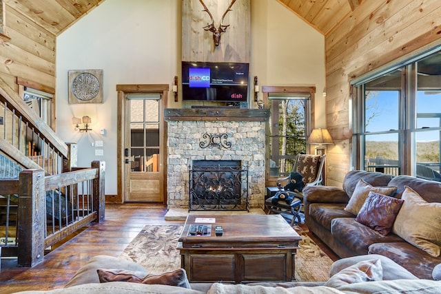 living room with a stone fireplace, hardwood / wood-style flooring, wood ceiling, and high vaulted ceiling