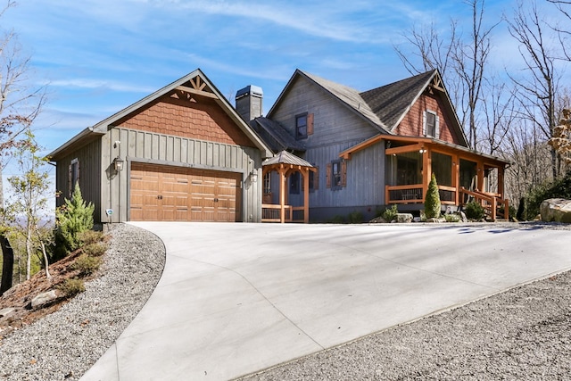 view of front of property featuring a porch, an attached garage, a chimney, and driveway