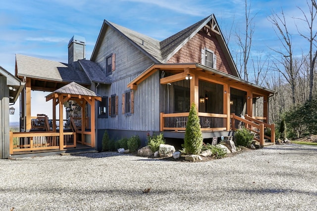 view of property exterior featuring roof with shingles, a porch, and a chimney