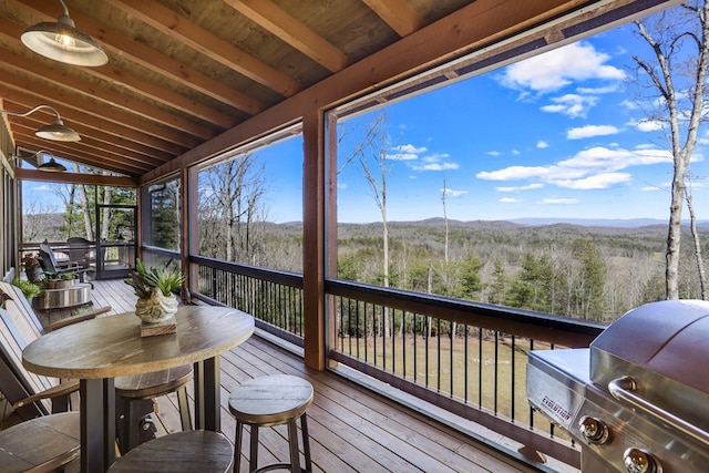 sunroom featuring lofted ceiling with beams, a forest view, and a mountain view