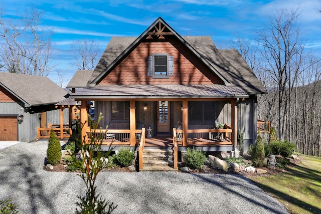 view of front of property with gravel driveway, covered porch, an attached garage, and a shingled roof