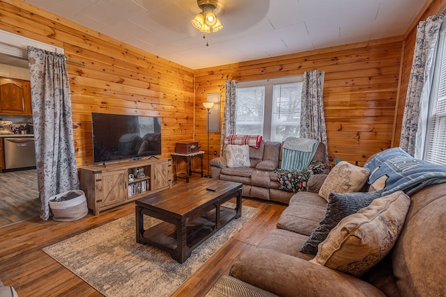 living room with ceiling fan, light hardwood / wood-style floors, and wood walls