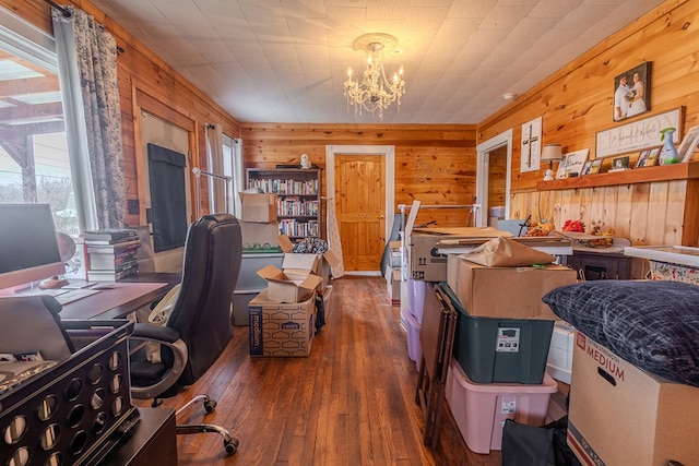 office area with a notable chandelier, dark wood-type flooring, and wood walls