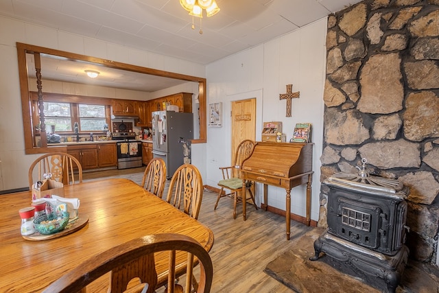 dining room with sink, light hardwood / wood-style flooring, and a wood stove