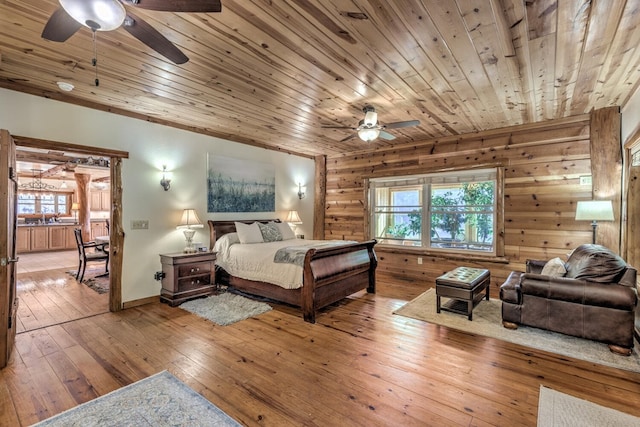 bedroom with wooden walls, light wood-type flooring, multiple windows, and wooden ceiling