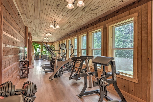 workout area featuring wood-type flooring, wooden walls, a chandelier, and wooden ceiling