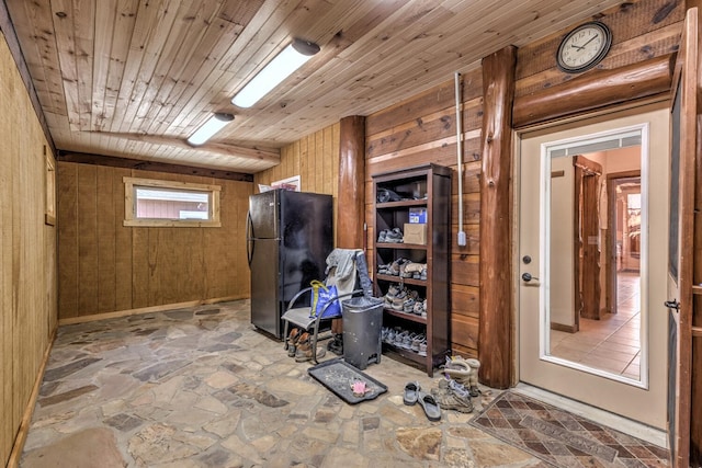 basement with wood ceiling, wooden walls, and black fridge