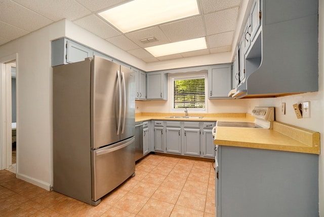 kitchen featuring appliances with stainless steel finishes, sink, gray cabinetry, and a drop ceiling