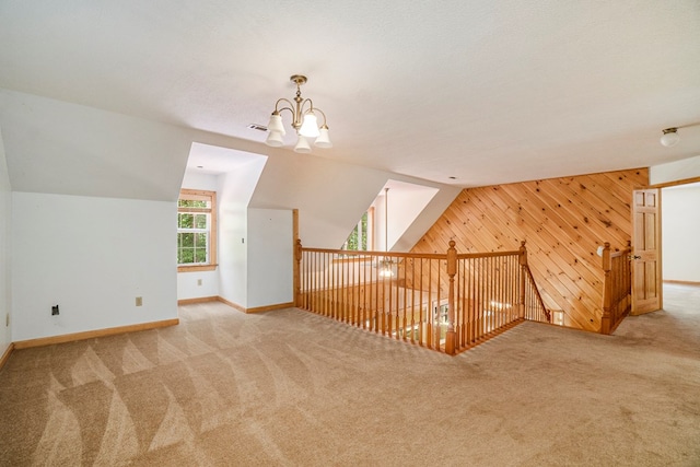 bonus room featuring lofted ceiling, light colored carpet, a textured ceiling, and wood walls