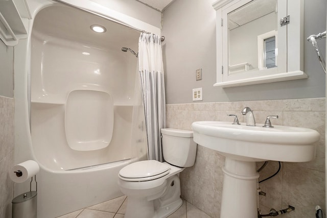 bathroom with tile patterned floors, toilet, shower / tub combo, and tile walls