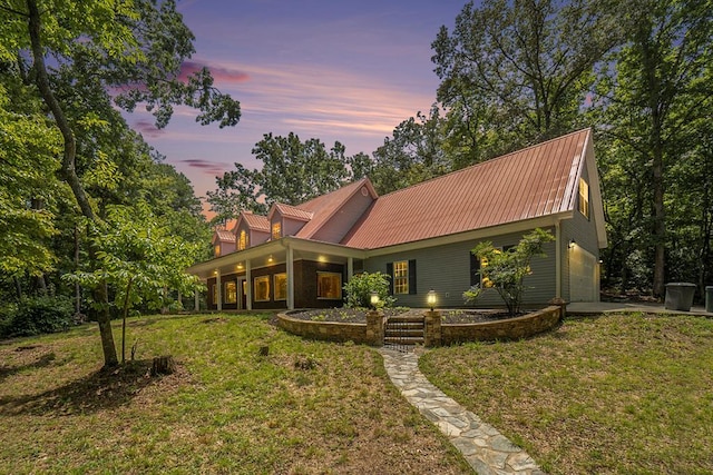 back house at dusk featuring a garage and a lawn