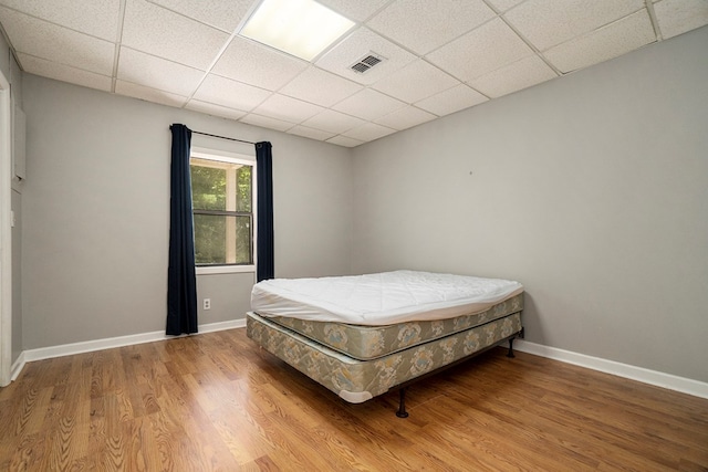 bedroom featuring hardwood / wood-style flooring and a paneled ceiling