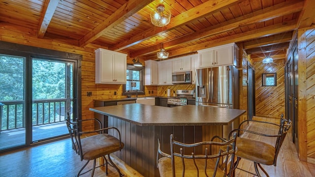 kitchen featuring a kitchen island, white cabinetry, beam ceiling, and stainless steel appliances