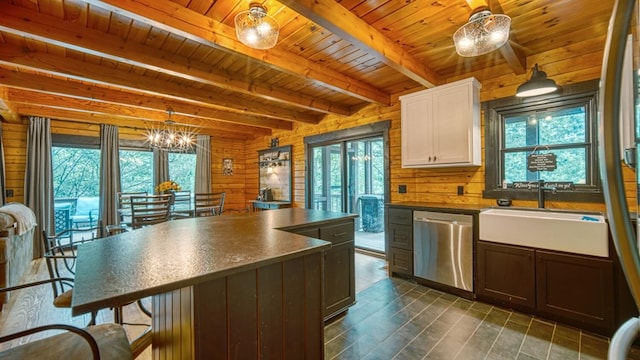 kitchen with wood walls, dishwasher, and hanging light fixtures