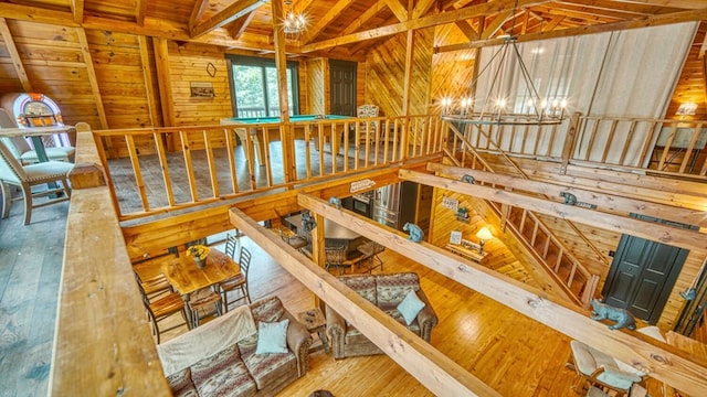 stairway featuring wood ceiling, wood-type flooring, an inviting chandelier, wooden walls, and lofted ceiling with beams