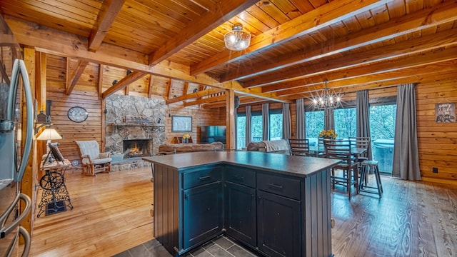 kitchen with a fireplace, wood walls, beamed ceiling, and a wealth of natural light