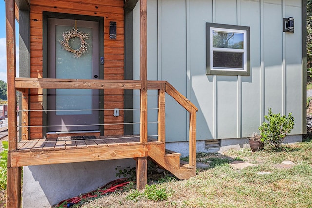 view of exterior entry featuring board and batten siding and crawl space