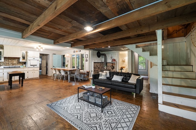 living room with stairs, a wood stove, beamed ceiling, wood ceiling, and dark wood-type flooring