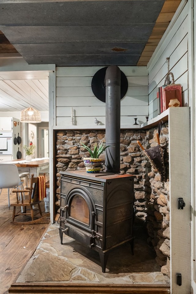 detailed view of a wood stove, wood finished floors, oven, wood walls, and wooden ceiling